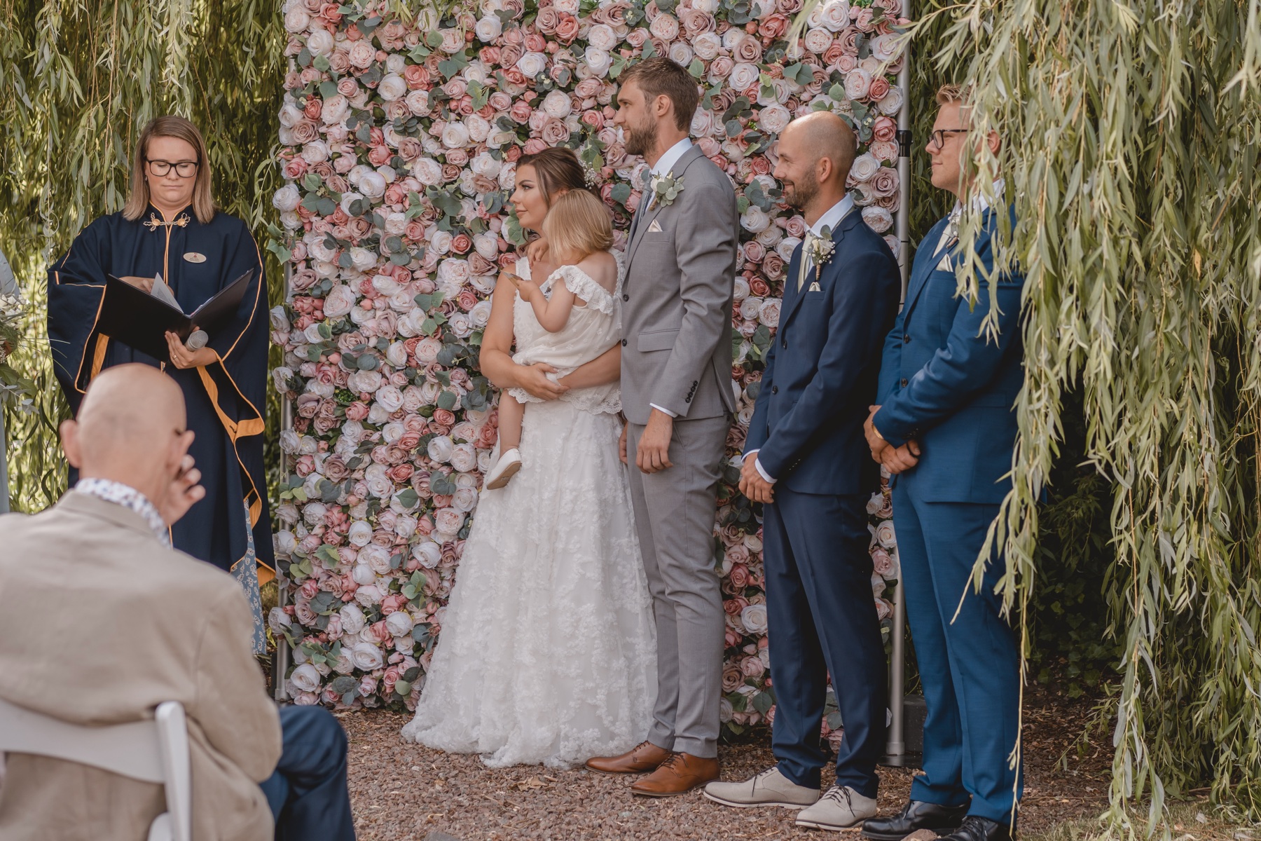 Bröllopsceremoni framför en blomstervägg